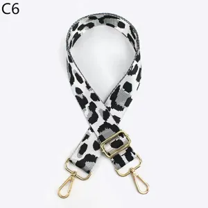 Detalle de correa de bolso con estampado de leopardo en blanco y negro con herrajes dorados.