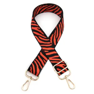 Close-up detail of red and black zebra pattern replacement bag strap with gold metal hardware.