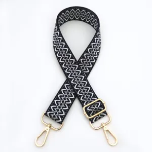 Vista dettagliata della tracolla di ricambio intrecciata in bianco e nero con hardware dorato.