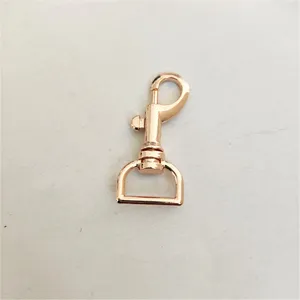 Primo piano di moschettone in metallo oro rosa, accessorio girevole per borse e portachiavi.