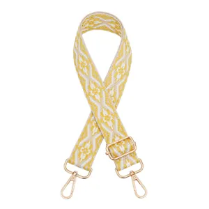 Close up of the ethnic style woven bag strap showing yellow geometric pattern and gold hardware.