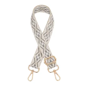 Detailed view of the woven ethnic style bag strap with adjustable gold tone hardware buckles.