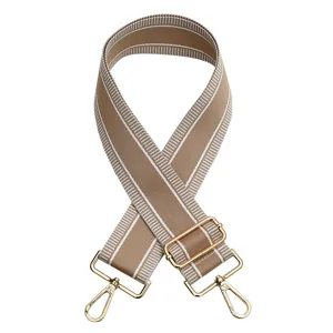 Detalle de la correa de bolso ancha tejida con hebillas metálicas doradas ajustables.