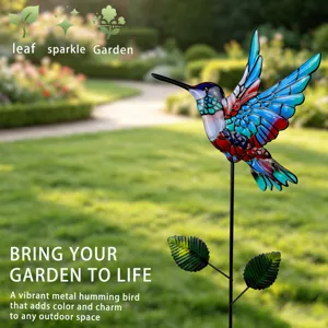 Vibrant metal hummingbird garden stake detail showing colorful stained wings and leaves.