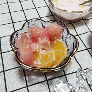 Nahaufnahme der klaren Glasblumenschüssel mit Goldrand, die ihre exquisite Blütenform zeigt.