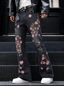 Detailed view of black washed flare jeans with pink cherry blossom embroidery and distressed rips.