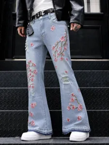Jean flare bleu clair pour homme avec broderie de fleurs de cerisier roses et détails déchirés.
