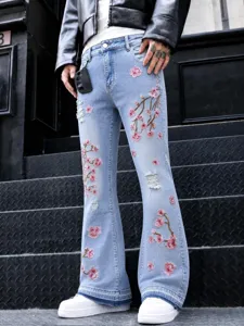 Vue détaillée de jeans évasés bleu clair pour homme avec broderie de fleurs de cerisier rose.