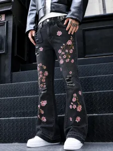 Men's stylish black flared denim jeans with pink cherry blossom embroidery and distressed details.