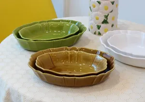 Ceramic oval baking dish detail, vintage wavy edge design, nested tableware set display.