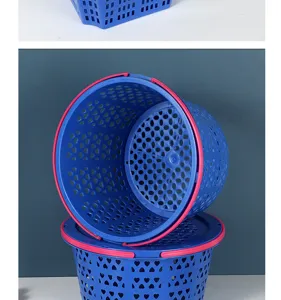 Gros plan détail du panier de fruits en plastique bleu avec poignée rose et motifs.