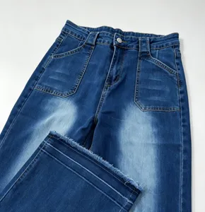 Close-up detail of high-waisted denim jeans with front patch pockets and raw frayed hem cuff.