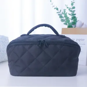 Trousse de maquillage matelassée noire avec poignée et fermeture pour le voyage.