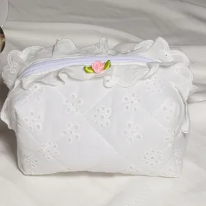 Detail view of the white quilted cosmetic bag featuring exquisite lace ruffles and a cute rose bow.