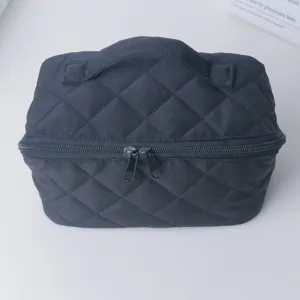 Détail de trousse de toilette matelassée noire, pochette souple rembourrée avec double zip.
