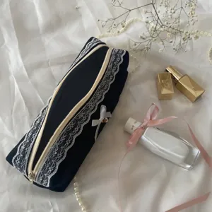 Detail view of a cute black velvet pencil case with white lace and bow for storage.