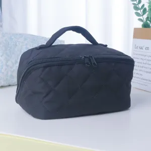 Gros plan sur la trousse de toilette noire matelassée avec texture douce et double fermeture.