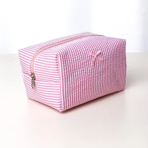 Pink white striped cosmetic bag and toiletry pouch with cute bow for daily travel storage.