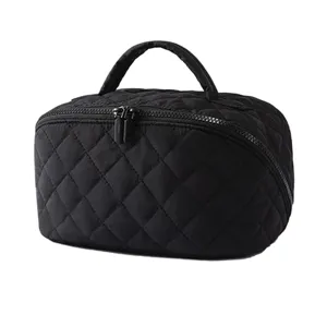 Détail de la trousse de toilette noire matelassée en tissu doux avec doubles fermetures éclairs.