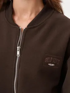 Women's casual brown zip-up sweatshirt detail, featuring metallic zipper and chest embroidery text.