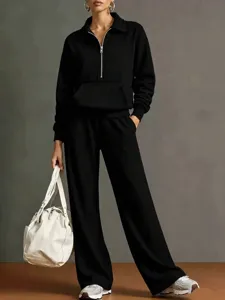 Primo piano sul colletto con zip e sul taglio ampio dei pantaloni della tuta nera.