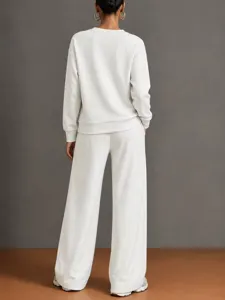 Detail view of the casual white two-piece sweatshirt and wide-leg trousers outfit.