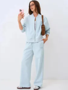 Detail view of casual light blue women's tracksuit jacket and wide leg trousers outfit.