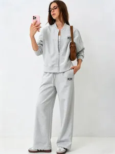 Detailed view of casual light grey tracksuit featuring zip jacket and wide-leg pants.