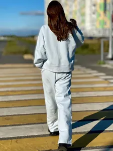 Outdoor street detail view of a casual light blue sweatshirt tracksuit worn by model.