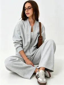 Detail view of casual grey zip-up hoodie and wide-leg sweatpants set worn by model sitting.