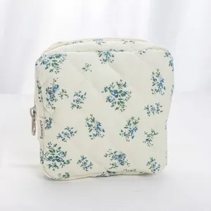 Detailed view of quilted cosmetic pouch with blue floral pattern and smooth zipper closure.