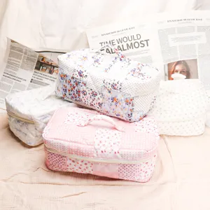 Quilted cosmetic bag with floral patchwork, portable handle and zip closure for travel storage.