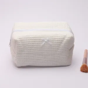 White waffle cosmetic bag with zipper and bow, portable travel makeup wash pouch detail.