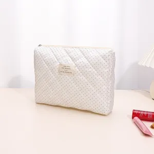 White quilted cosmetic bag detail close-up showcasing soft padded fabric and neat zipper closure.