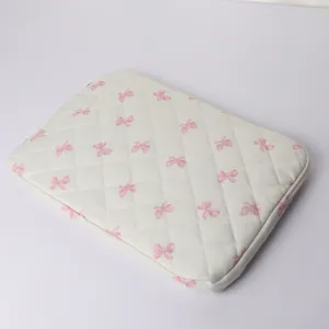 Dettaglio della custodia trapuntata per laptop con fiocchi rosa e un design morbido e imbottito.