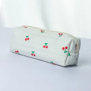 Close-up detail of white quilted pencil case with cute red cherry pattern and secure zipper.