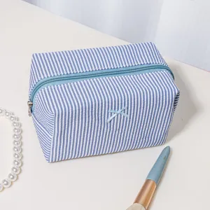 Detail shot of blue white striped cosmetic bag zipper closure portable toiletry travel pouch
