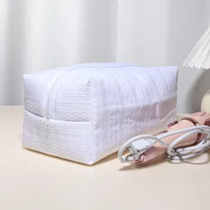Close up detail of white quilted storage bag featuring smooth zipper and styling tool prop.