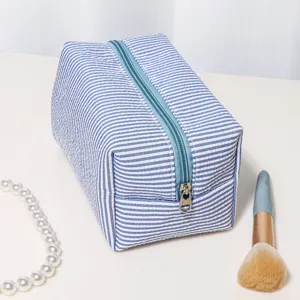 Blue and white striped seersucker makeup pouch detail, showing zipper and fabric texture.