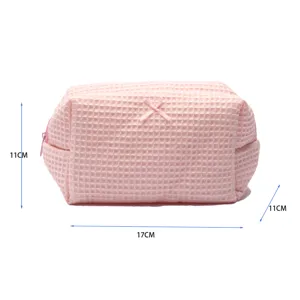 Pink waffle cosmetic bag detail, soft fabric makeup pouch with cute bow and size dimensions.