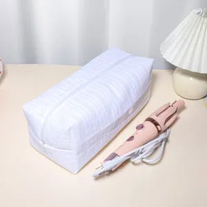 White quilted storage bag for hair styling tools and cosmetics with zipper closure.