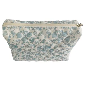 Detailed close-up of quilted cosmetic pouch with charming blue floral pattern and zipper.