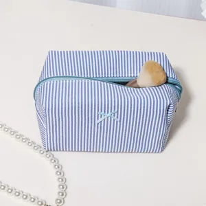 Blue and white striped cosmetic bag detail view, featuring a cute bow and secure zipper.