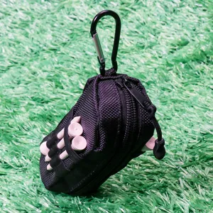 Close-up detail of portable black golf storage pouch with carabiner and tees on green turf.
