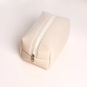 Close-up view of a soft beige corduroy cosmetic bag with white zipper detail for travel.
