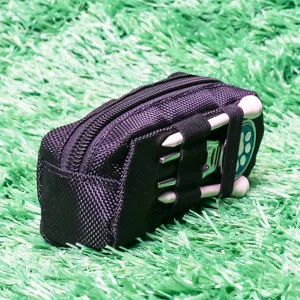 Detailed view of black nylon golf storage pouch with tees and divot tool on grass backdrop.