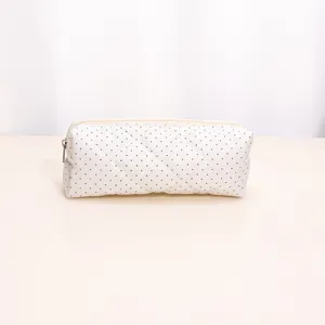 Detailed view of the white quilted cosmetic bag with black polka dots, showing fine stitching.
