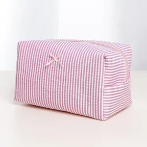 Detailed close-up view of the pink striped cosmetic bag with cute bow and smooth zipper.