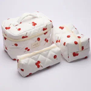 Quilted cosmetic bag set detail view, featuring white fabric with cute red cherry pattern and zips.