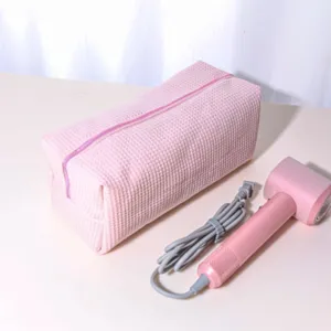 Pink waffle storage bag and hair dryer detail view showing soft padded texture and portable size.